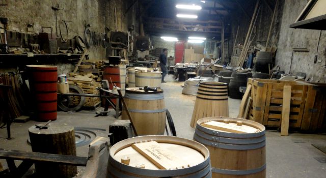 Vista del taller de la tonelería propia, con las herramientas dispuestas en la pared, barricas y otros recipientes en construcción.
