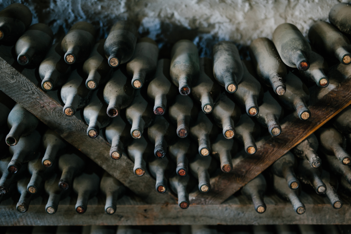 Wine bottles with corks, full of dust, in niches in the cellar. Photo by Julia Volk from Pexels.
