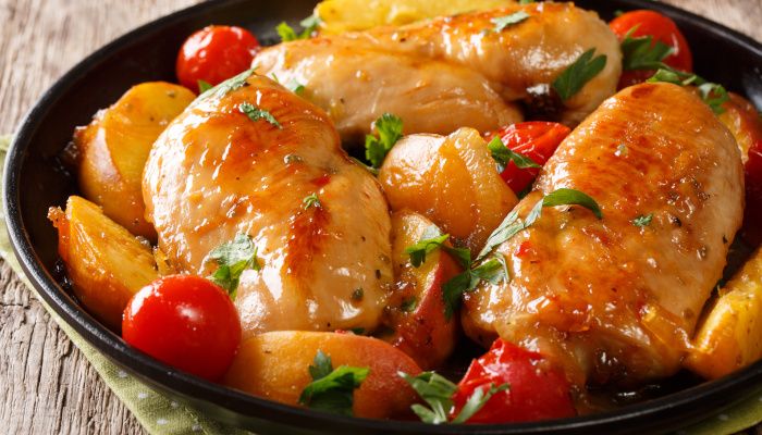 Baked chicken breast with peaches, tomatoes and onions on a plate on a table.