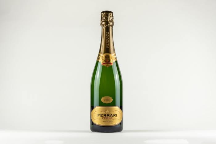 Green champagne bottle on white surface. Photo by Edoardo Tommasini from Pexels.