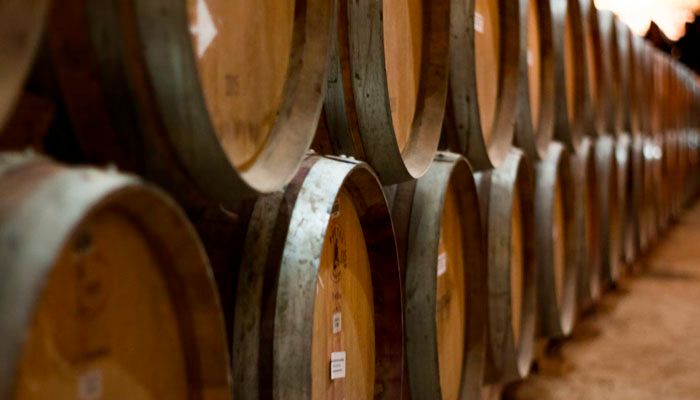 Two lines of barrels stored in a winery, one over the other.