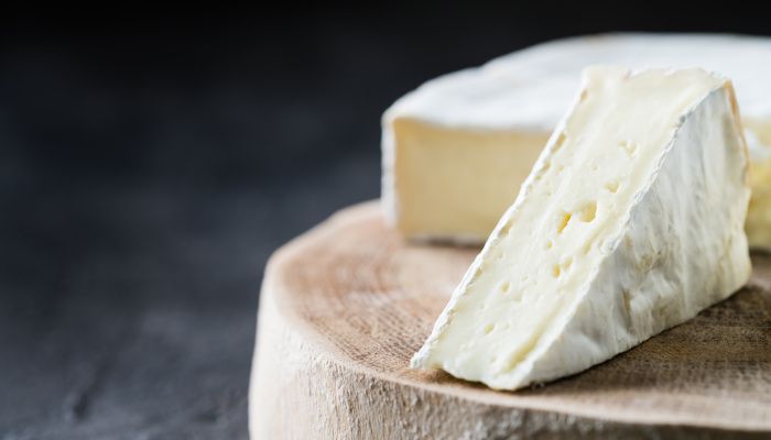 Triángulo de queso brie sobre una tabla de madera.