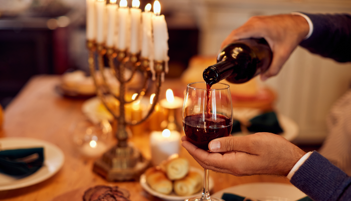 A Jewish man pouring wine at dining table on Hanukkah.