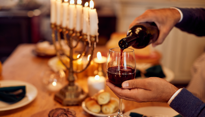  A Jewish man pouring wine at dining table on Hanukkah.